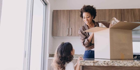 A mom packing a box while her daughter looks at her