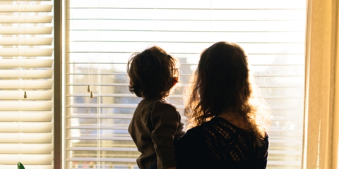 mother carrying child while looking out the window