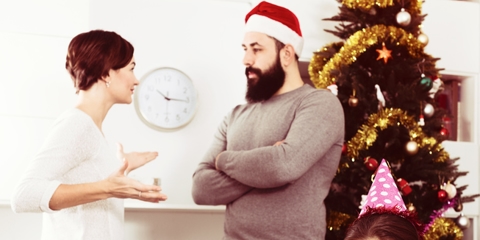 Parents arguing in front of Christmas tree and sad child