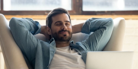 Man leaning back with hands behind head.