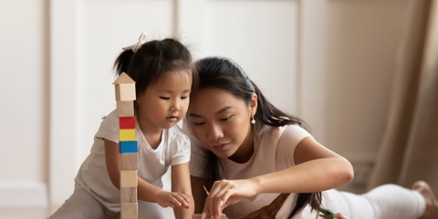Mother and daughter on floor playing with blocks.