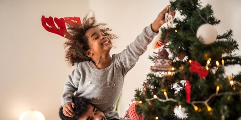 Young girl putting ornaments on the Christmas tree.