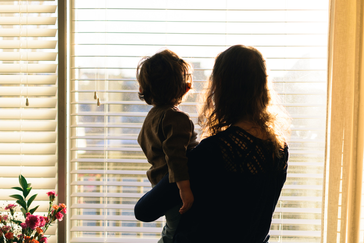 mother carrying child while looking out the window