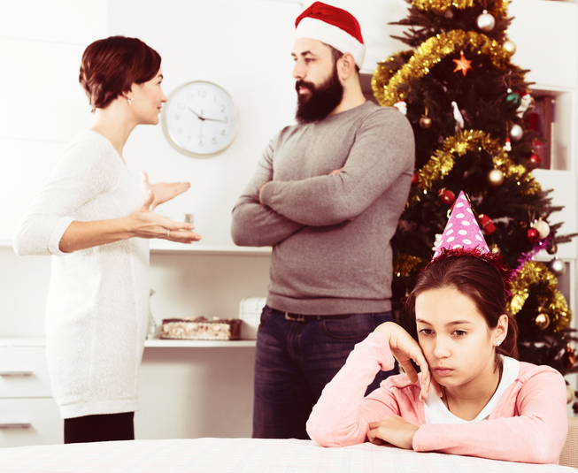 Parents arguing in front of Christmas tree and sad child