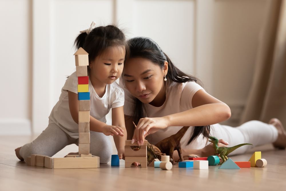 Mother and daughter on floor playing with blocks.