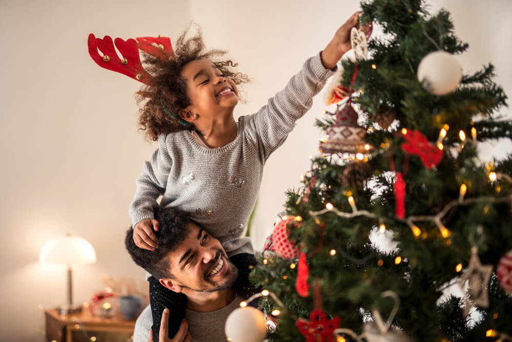 Young girl putting ornaments on the Christmas tree.
